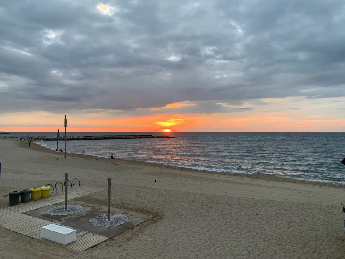 Alba arancione sulla spiaggia con le docce e il molo