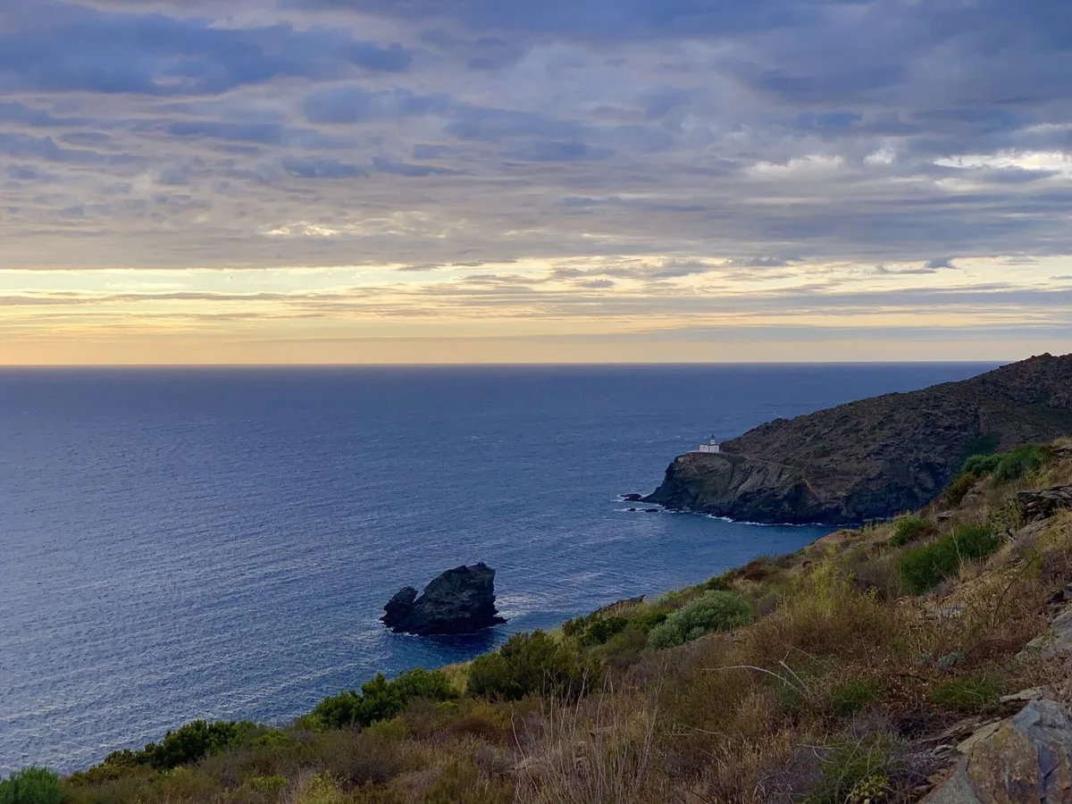 Costa rocciosa con un isolotto sul mare sotto un cielo nuvoloso