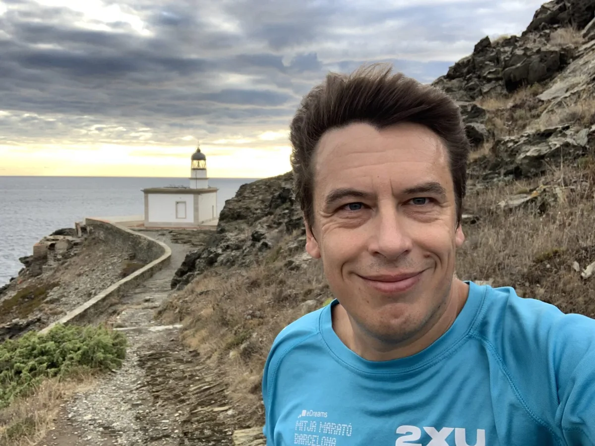 Selfie in maglia azzurra con il faro di Cala Nans alle spalle