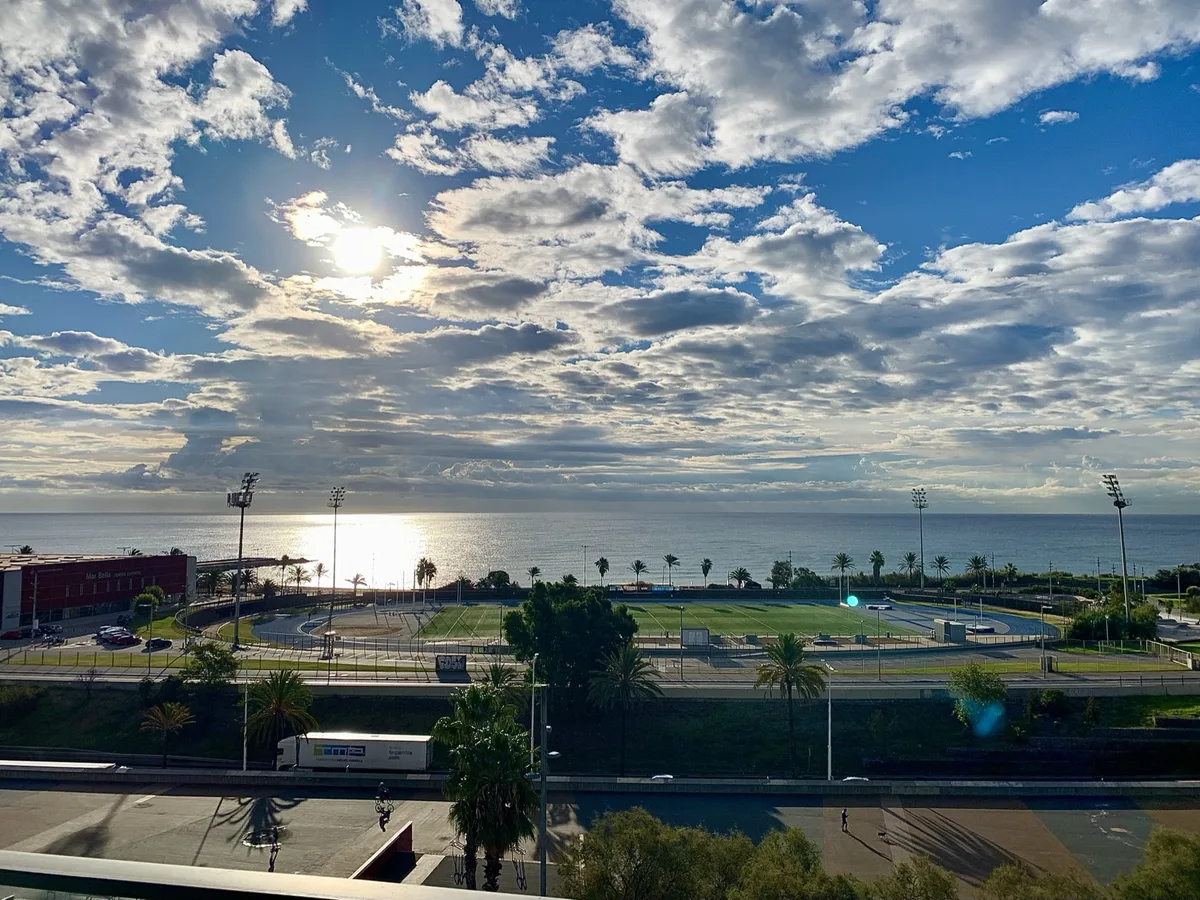 Sole tra le nuvole sul mare visto dall'alto con un campo sportivo