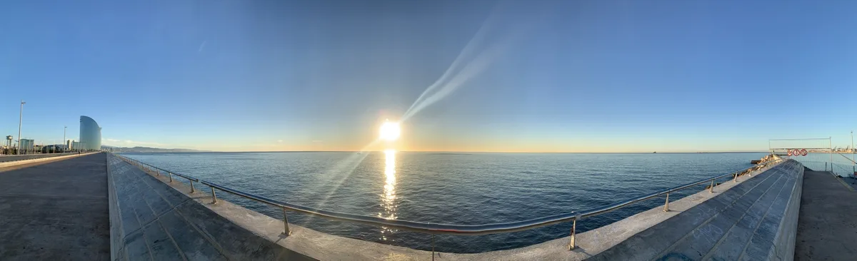 Panorama del molo sul mare con il sole in controluce