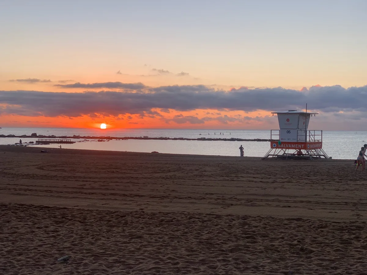 Alba rossa con una torretta del bagnino sulla spiaggia