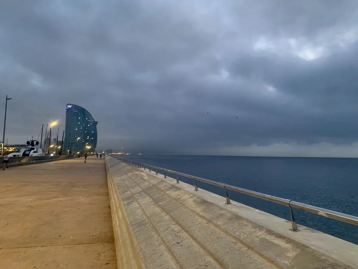 Molo con l'Hotel Vela di Barcellona sotto un cielo grigio