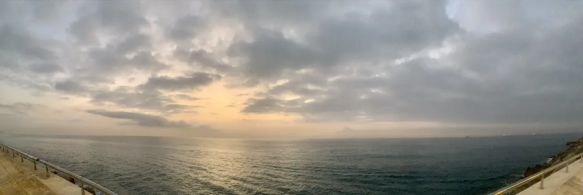 Panorama del mare al tramonto sotto un cielo nuvoloso