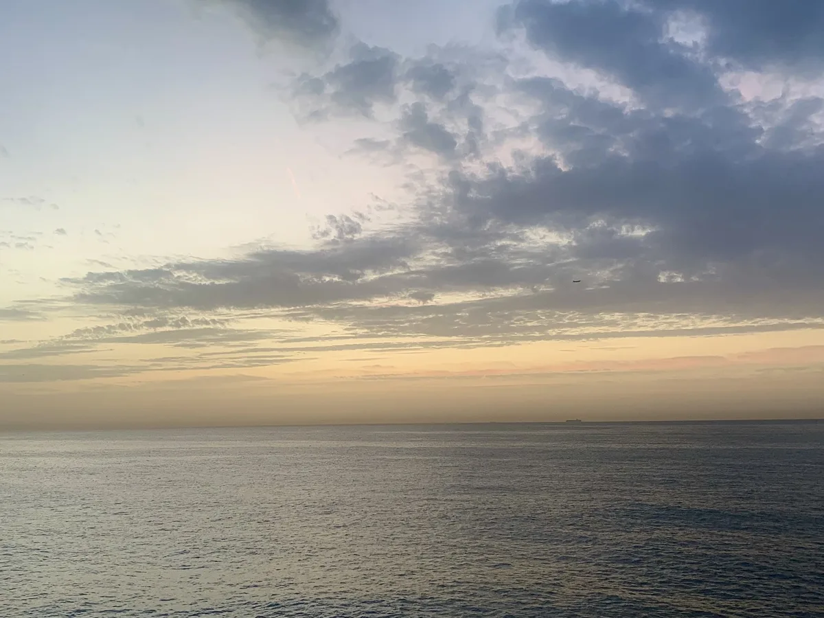 Mare calmo sotto un cielo con nuvole grigie e azzurre