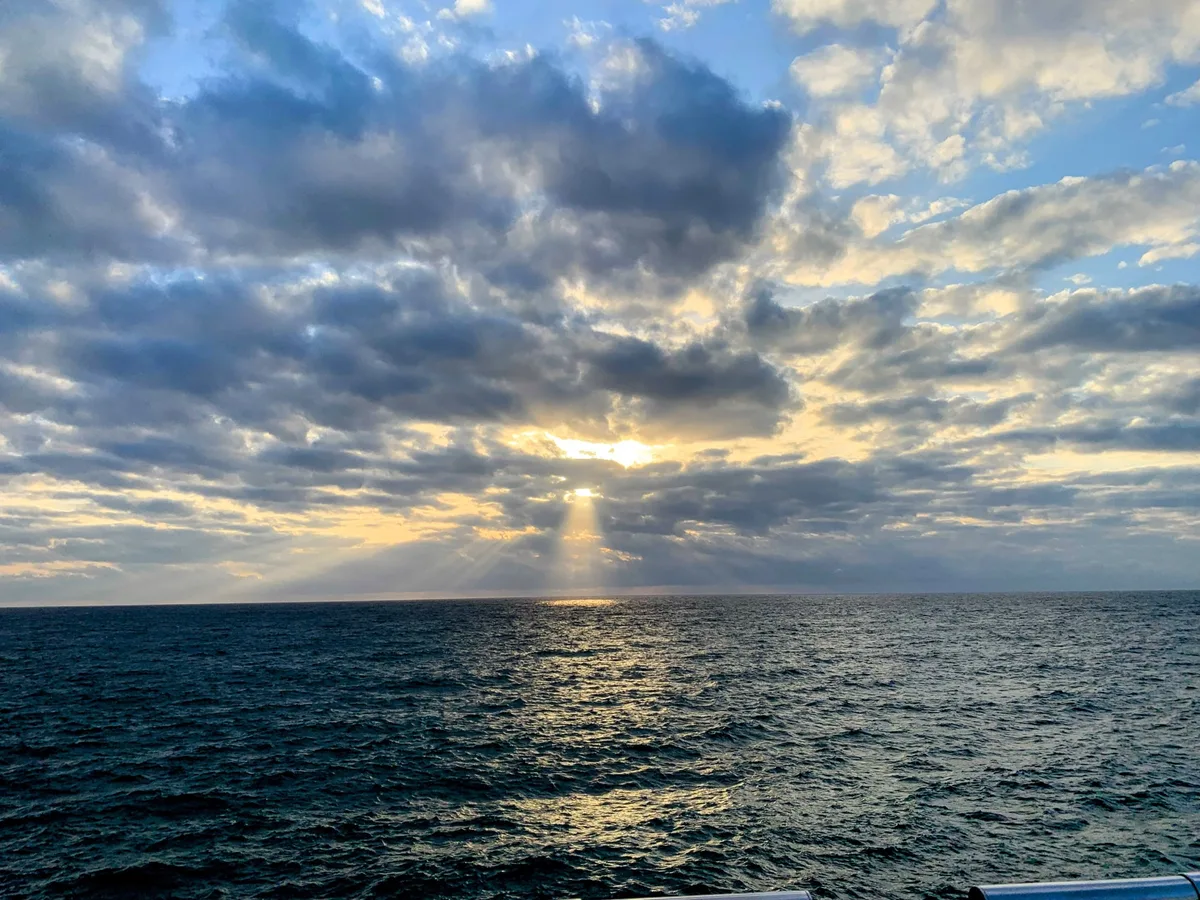 Raggi di sole che bucano le nuvole sul mare