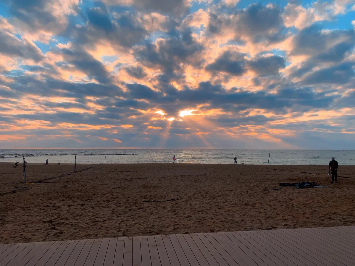 Raggi di sole tra le nuvole sulla spiaggia con una passerella di legno