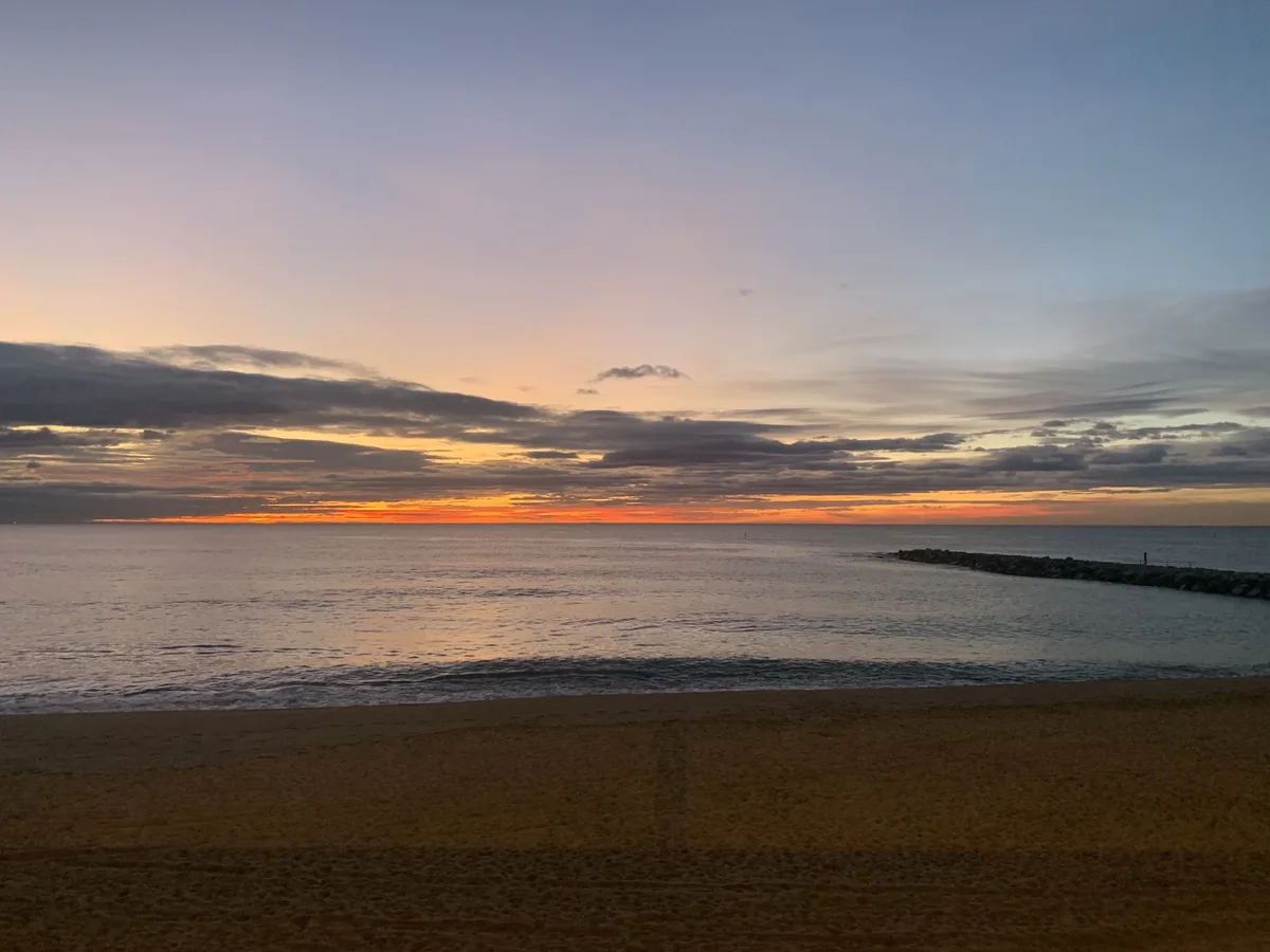 Alba con il cielo arancione sul mare e un molo