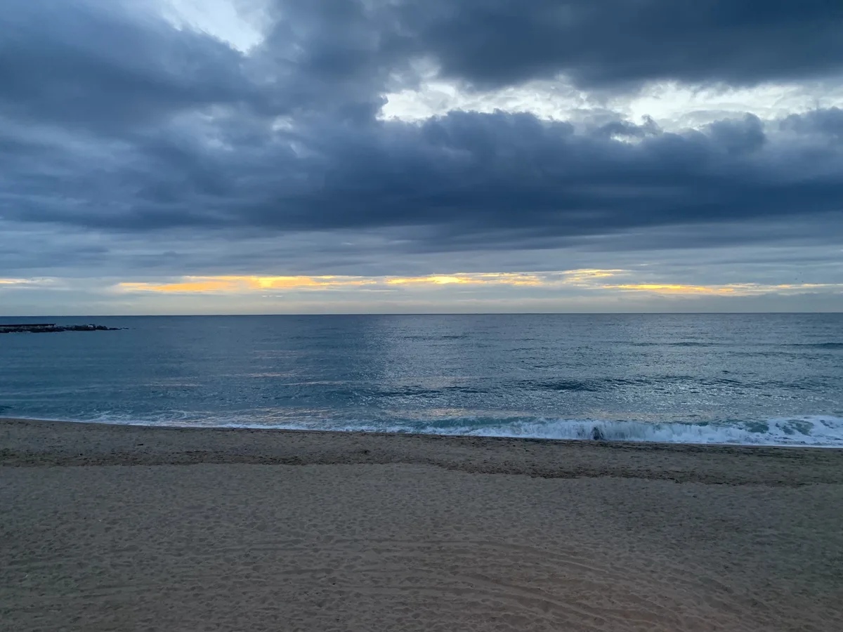 Spiaggia con nuvole scure sul mare calmo
