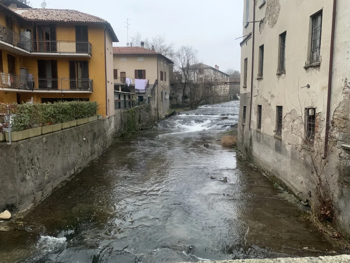 Torrente con una piccola cascata tra le case di un paese