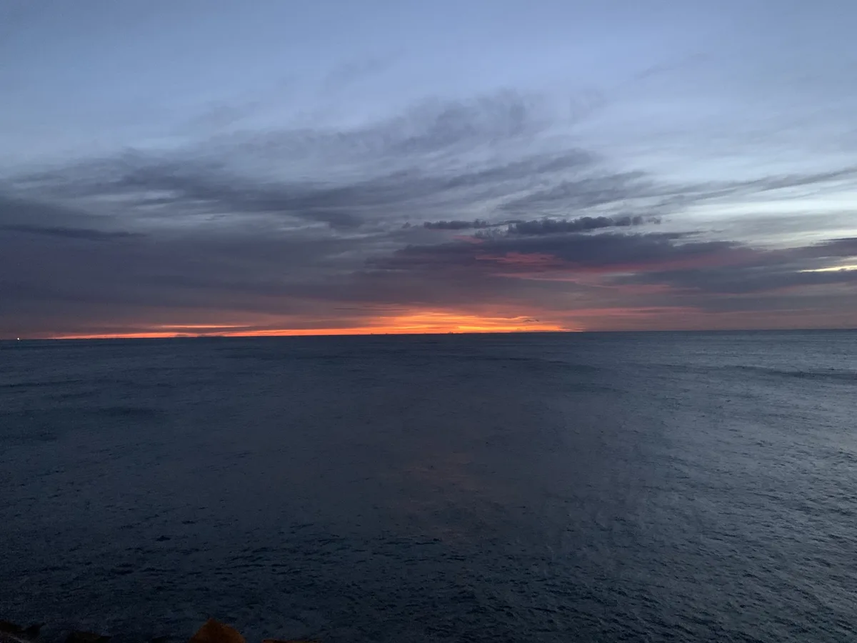 Alba sul mare con una striscia arancione sotto le nuvole