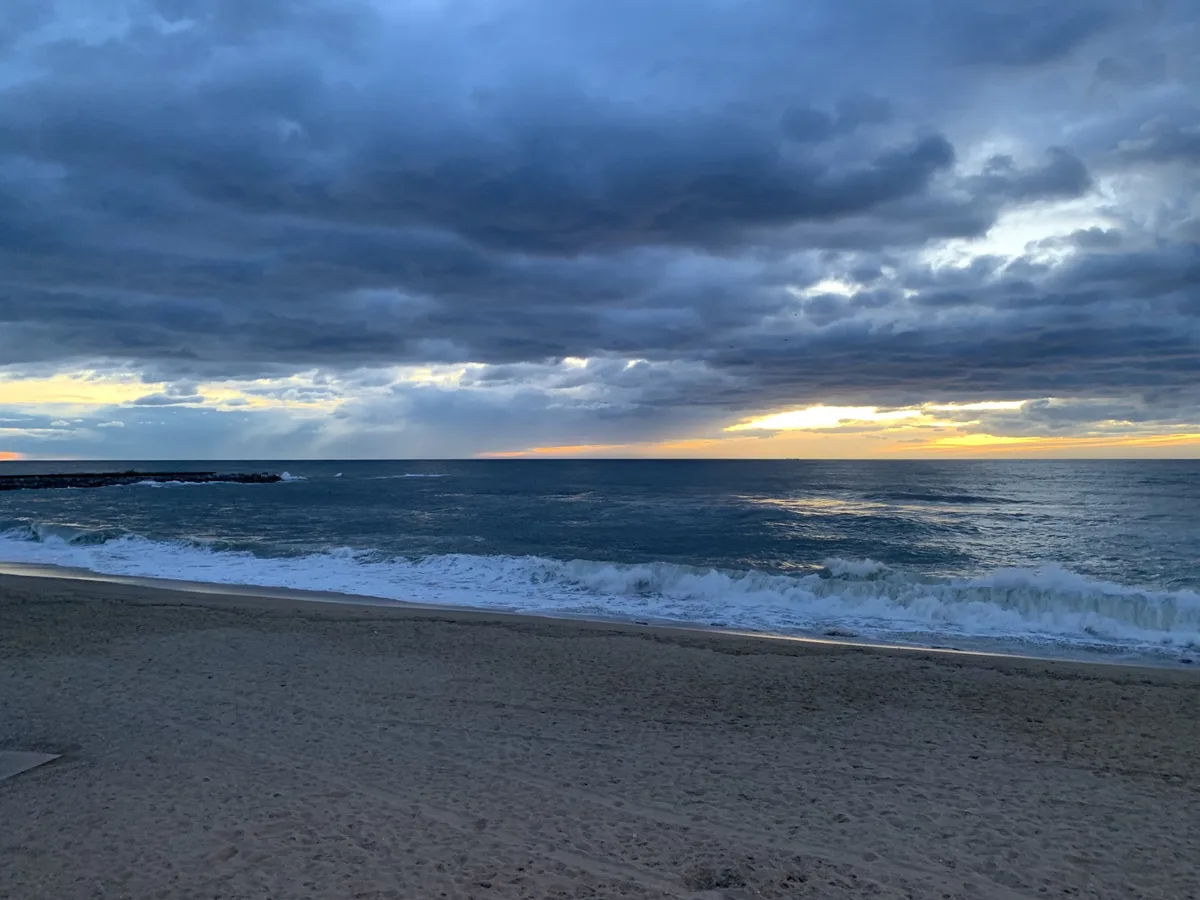 Spiaggia con onde sotto un cielo scuro e nuvoloso