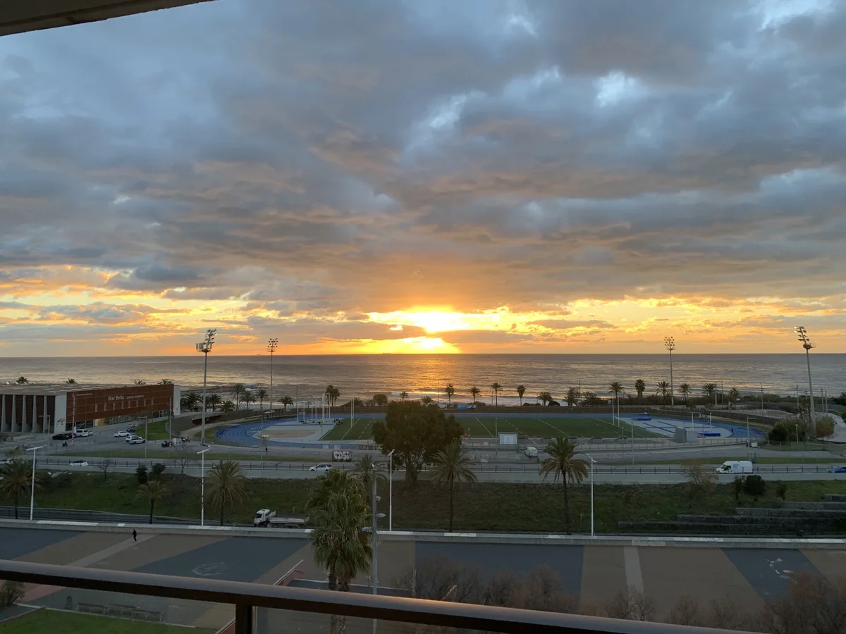 Alba arancione sul mare vista da un balcone sopra un campo sportivo