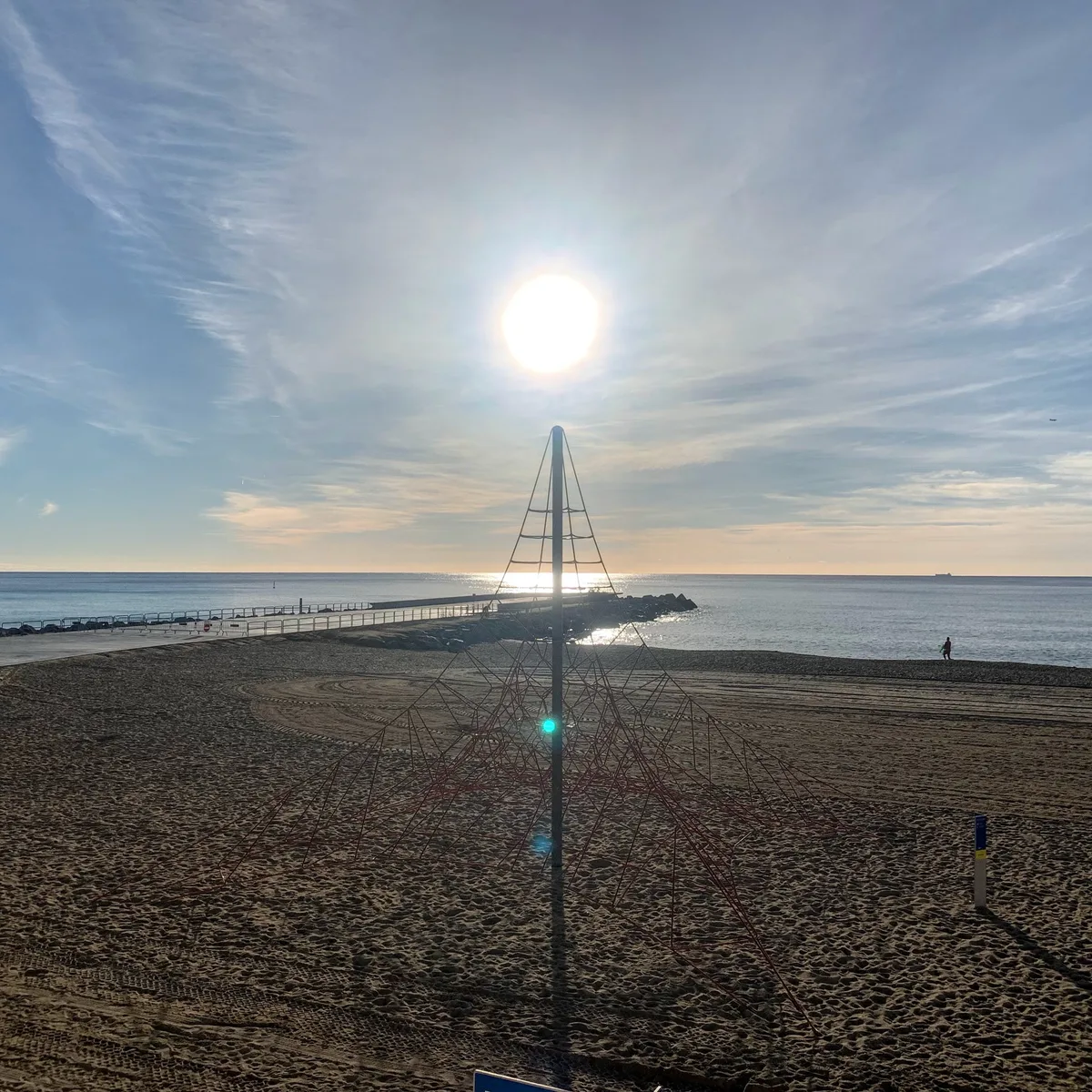 Sole sopra il mare dietro una struttura a piramide in spiaggia