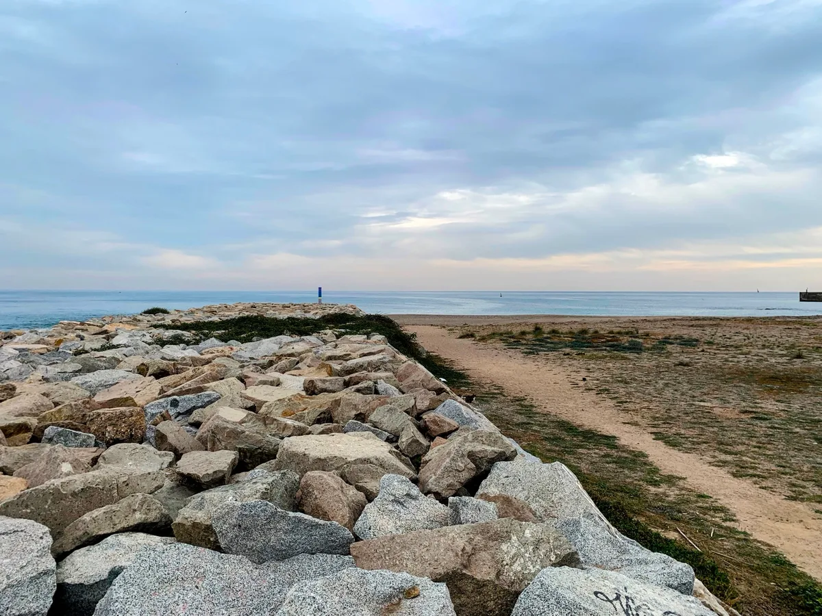 Sentiero sterrato lungo una scogliera di massi sul mare