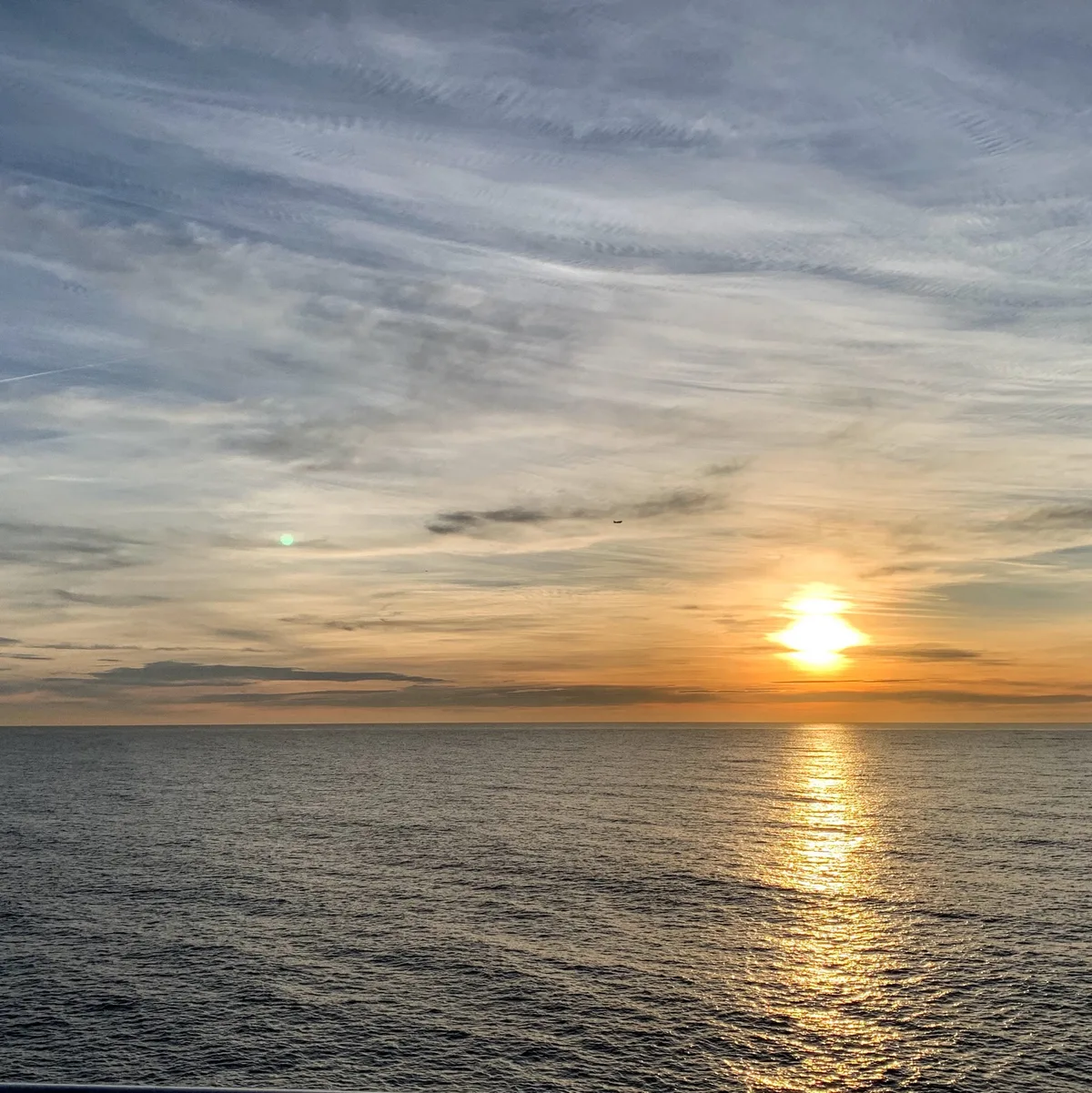 Sole che sorge sul mare con riflessi arancioni