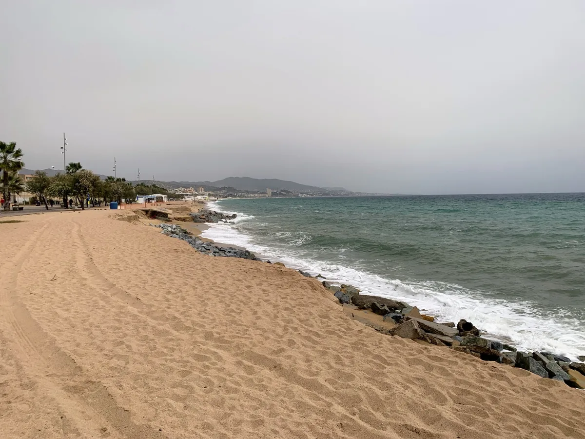 Spiaggia con onde e frangiflutti sotto un cielo velato