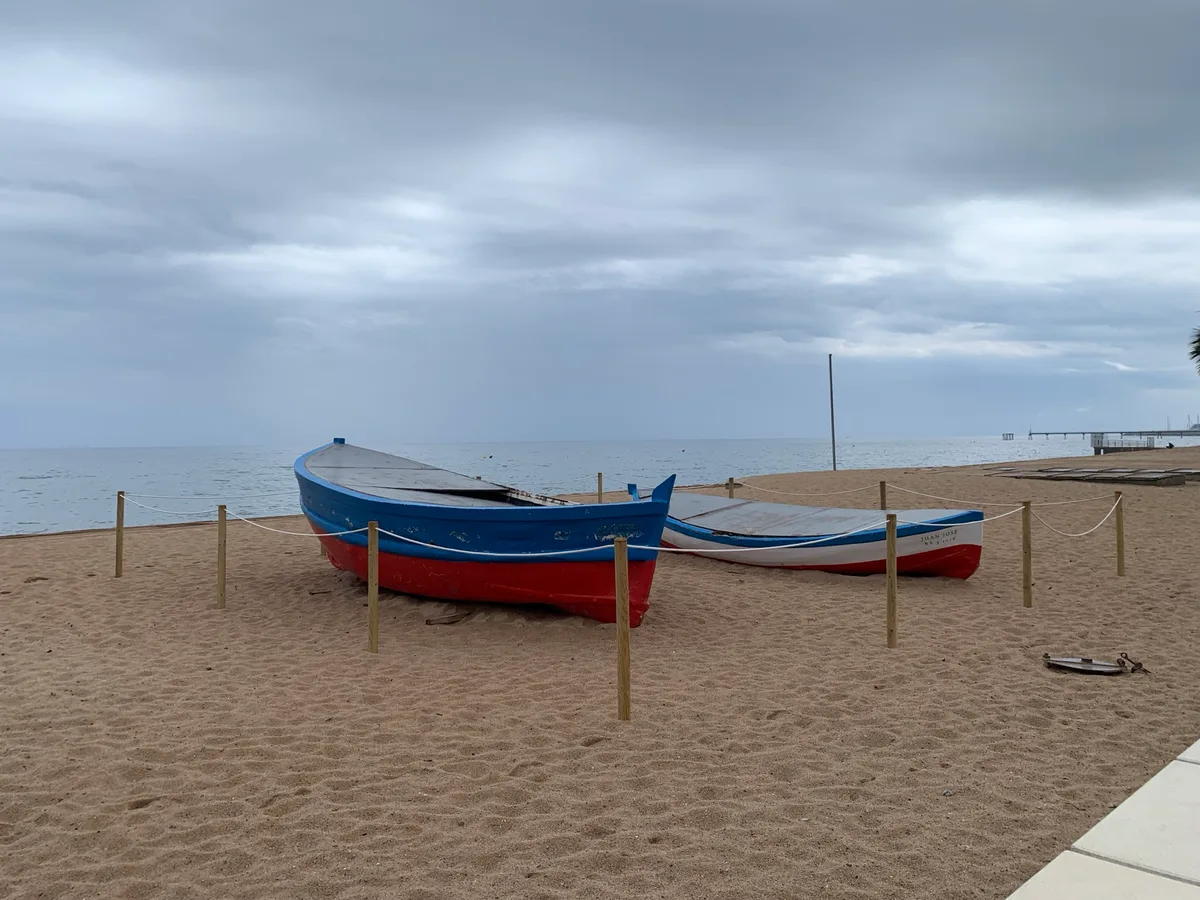 Barche da pesca sulla spiaggia con il molo sullo sfondo