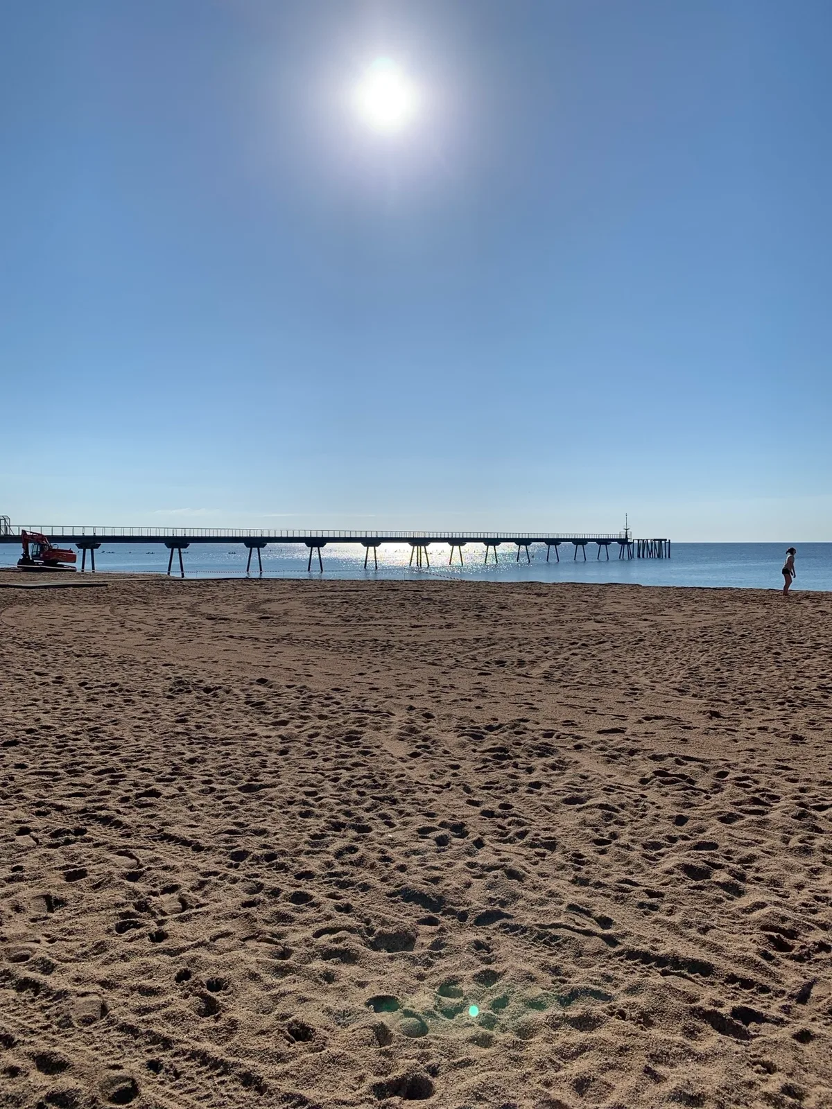 Spiaggia con il molo di Badalona e il sole alto