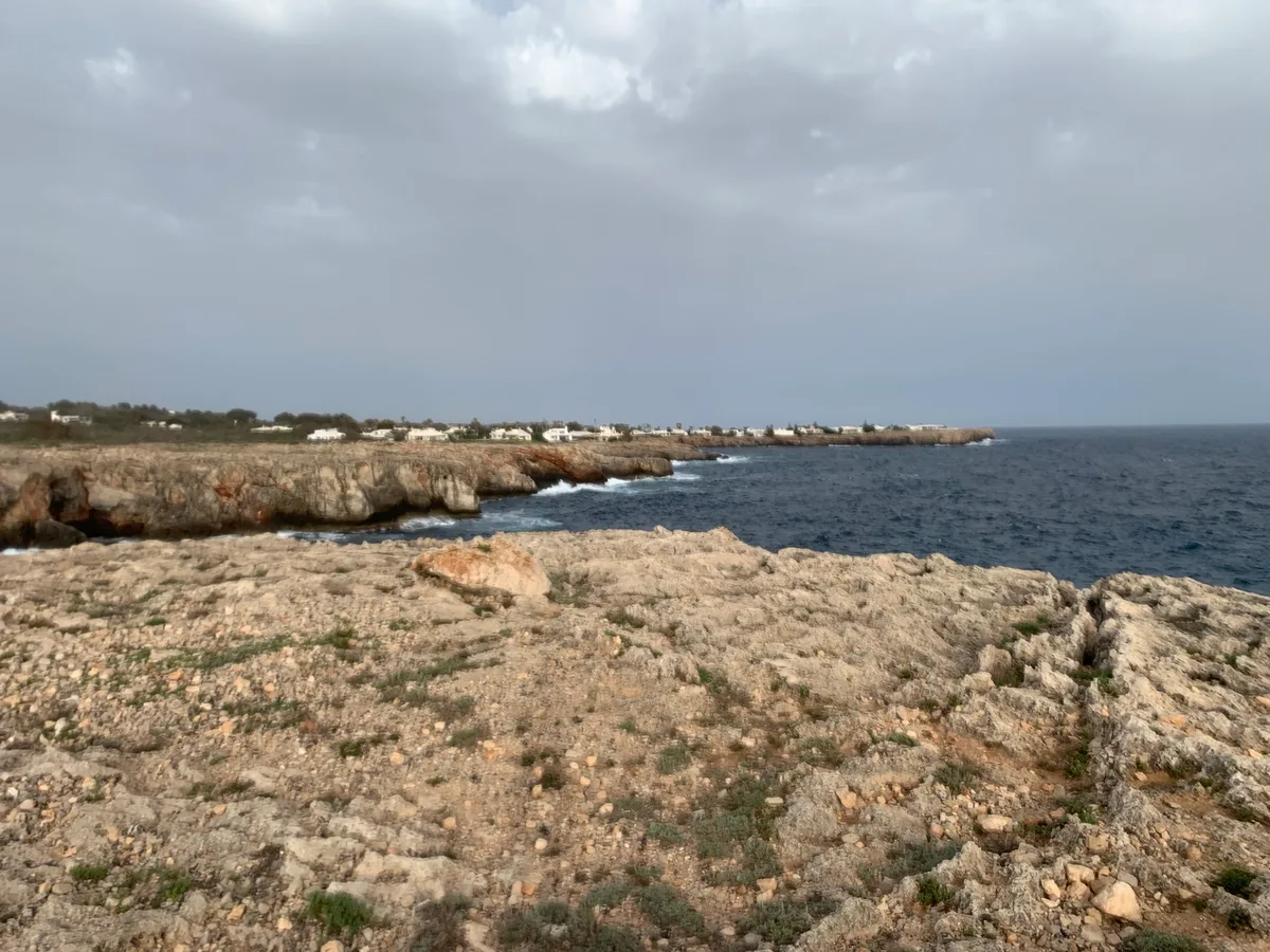Costa rocciosa con il mare scuro sotto un cielo nuvoloso