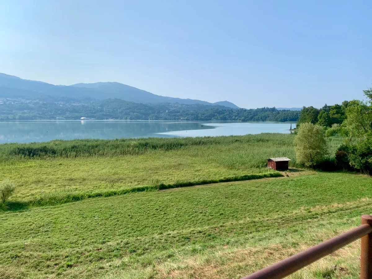 Prato in riva al lago con una piccola baita e le colline