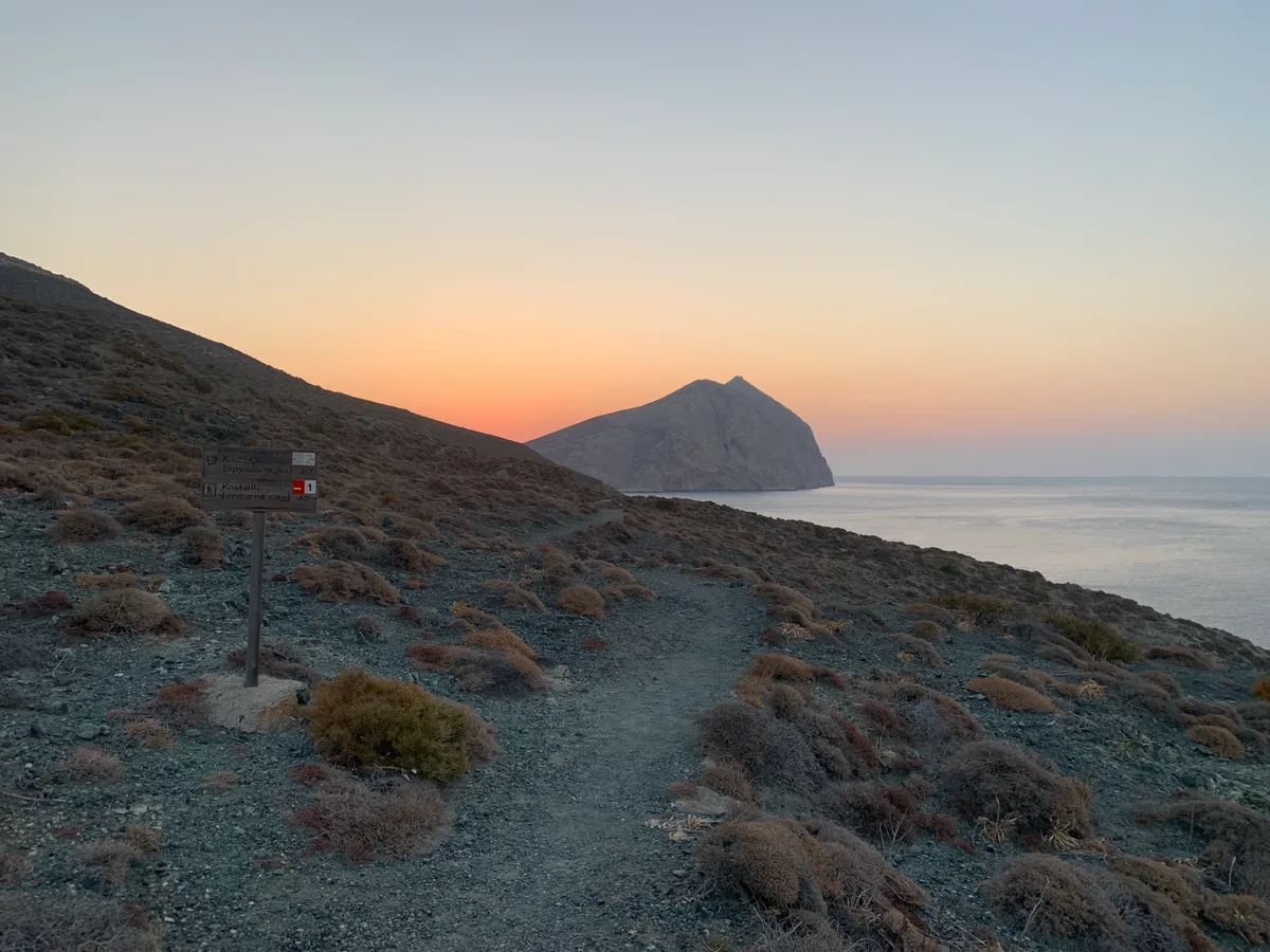Sentiero in collina al tramonto con un isolotto sul mare
