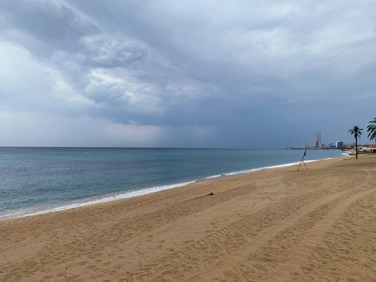 Spiaggia con il mare calmo e le nuvole cariche di pioggia