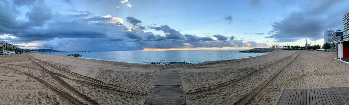 Panorama di una spiaggia con la passerella di legno sotto un cielo nuvoloso