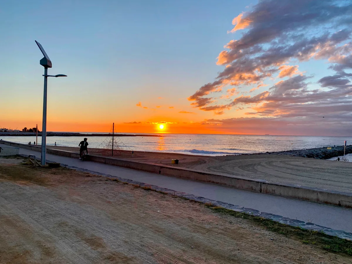 Alba arancione sul mare vista dal lungomare con i lampioni