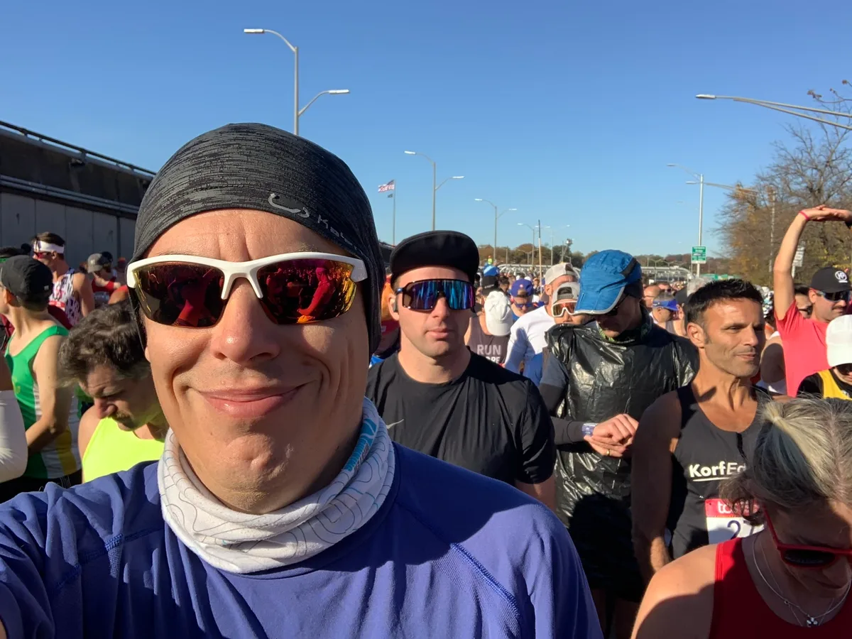 Selfie sorridente con occhiali da sole e scaldacollo nell'area di partenza della Maratona di New York