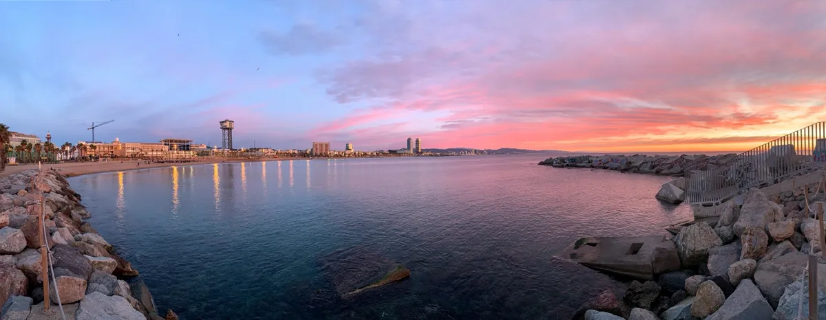 Panorama della baia di Barcellona al tramonto rosa dagli scogli