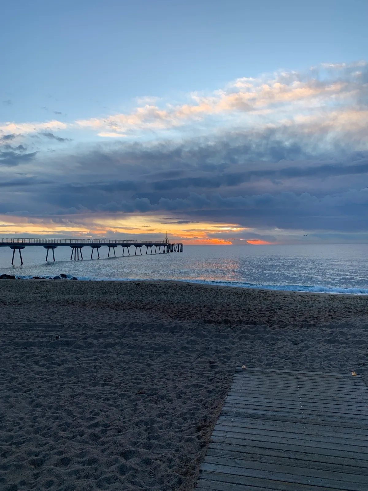 Alba con il molo di Badalona e la passerella di legno sulla sabbia
