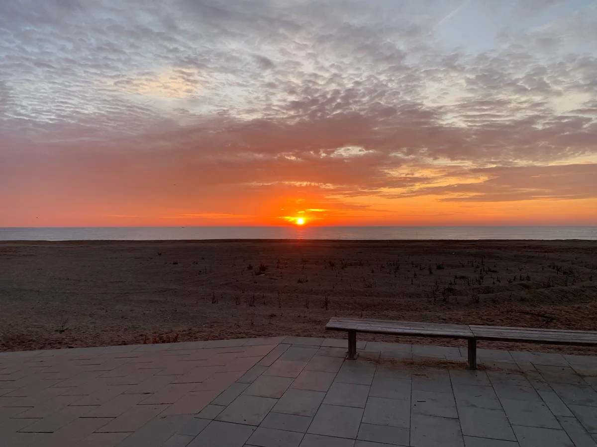 Alba arancione sul mare vista da una terrazza con panchina