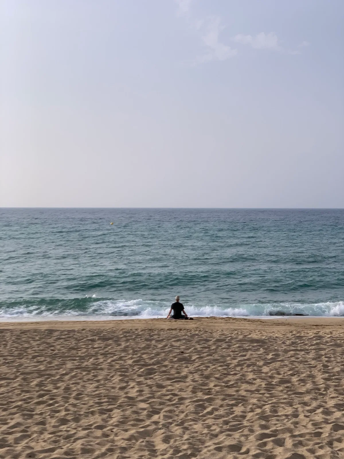 Mare calmo con una persona seduta sulla riva