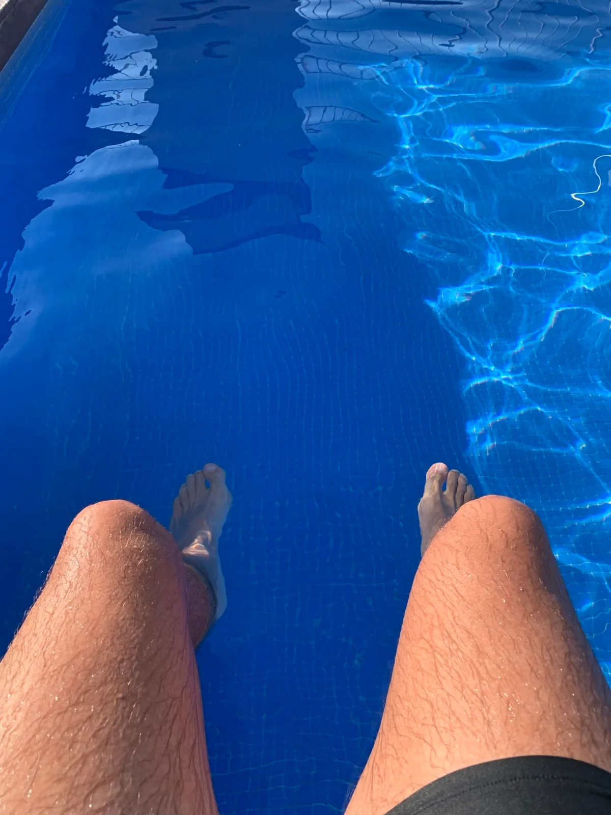 Gambe a bordo piscina nell'acqua azzurra