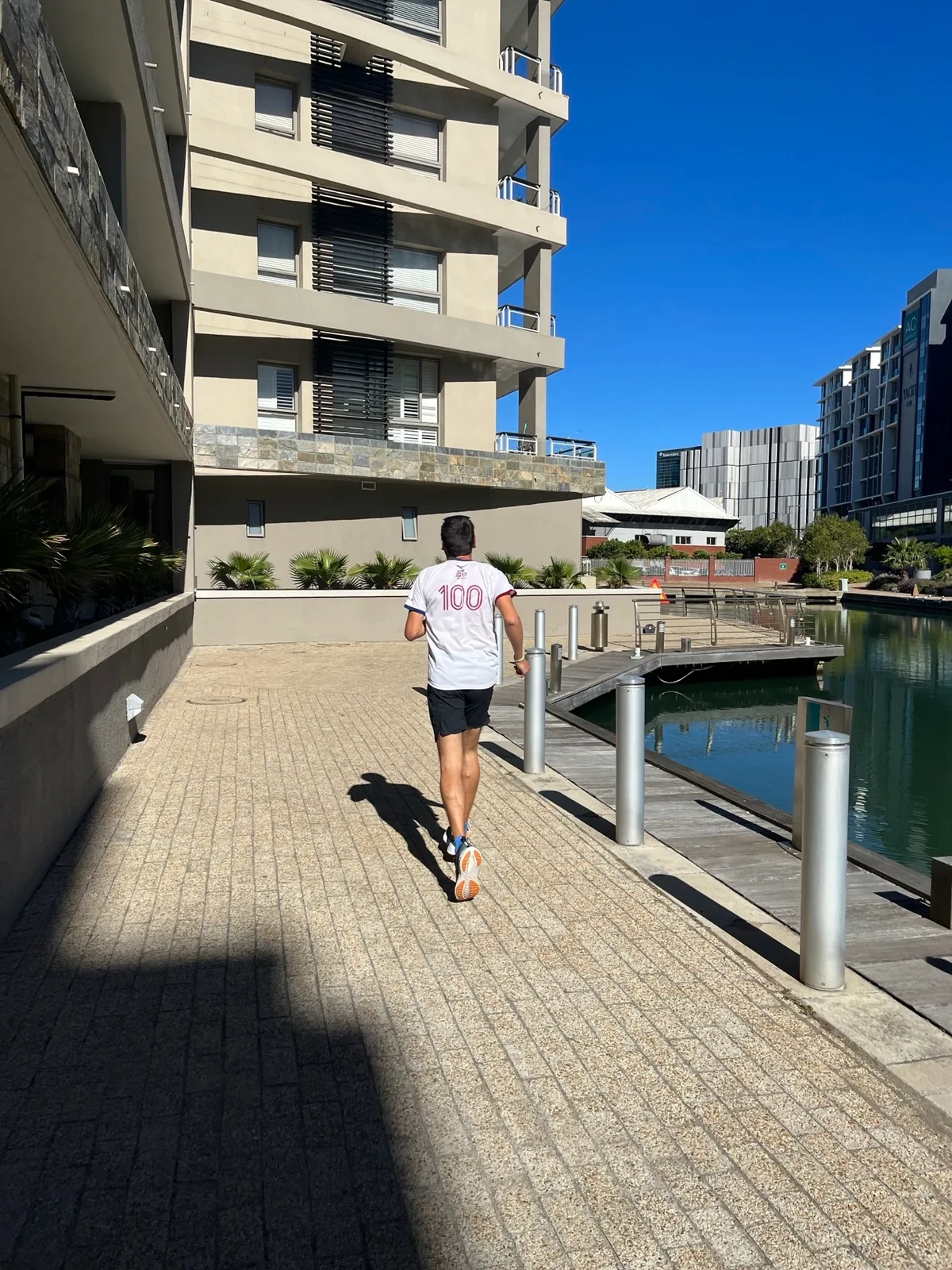 Corridore di spalle lungo una passerella vicino a un canale
