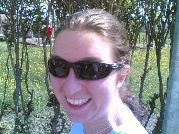 Selfie sorridente con occhiali da sole in un bosco con fiori gialli