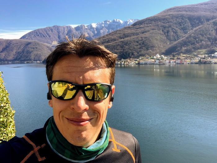 Selfie con occhiali da sole e scaldacollo sul lago con le montagne dietro