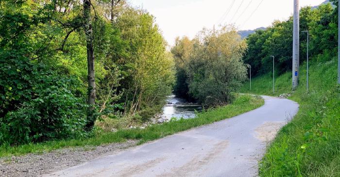 Strada asfaltata che costeggia un torrente nel verde