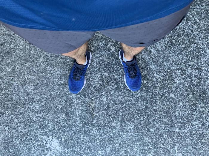 Scarpe da corsa blu e gambe viste dall'alto sull'asfalto
