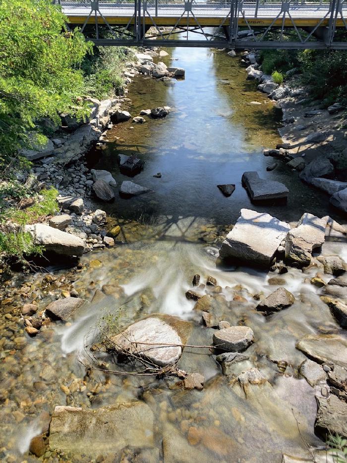 Torrente tra i sassi con un ponte sullo sfondo