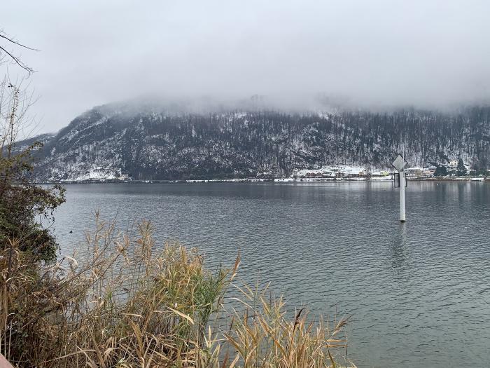 Lago con le montagne innevate e le nuvole basse