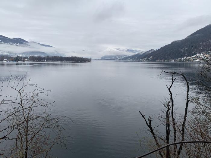 Lago calmo con le montagne innevate e un paese sulla riva