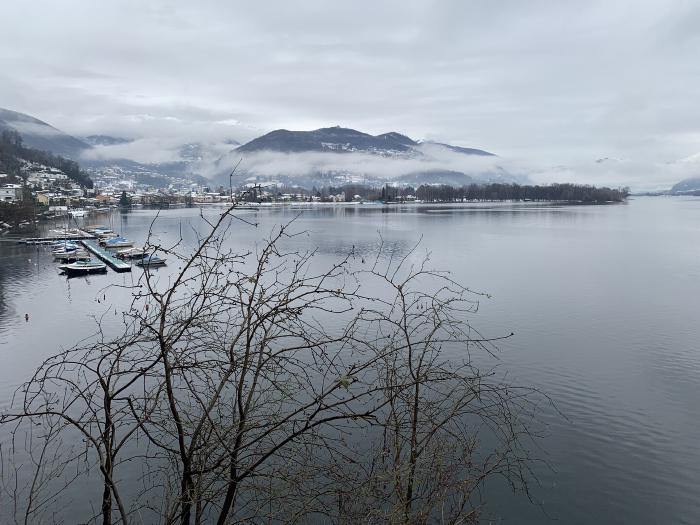 Lago con un pontile e le montagne nelle nuvole