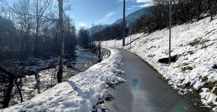 Pista ciclabile lungo un torrente tra la neve