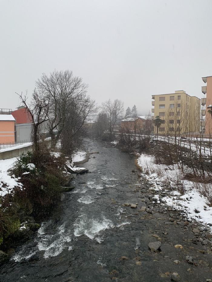 Torrente tra la neve con case sullo sfondo
