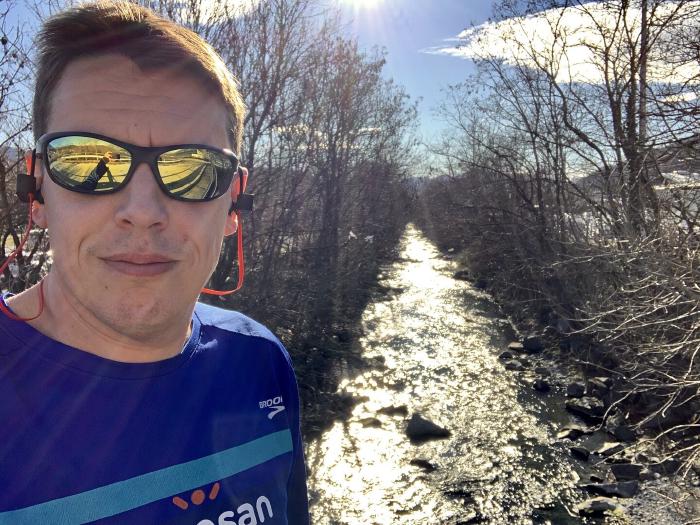Selfie con occhiali da sole a specchio e maglia blu lungo un torrente