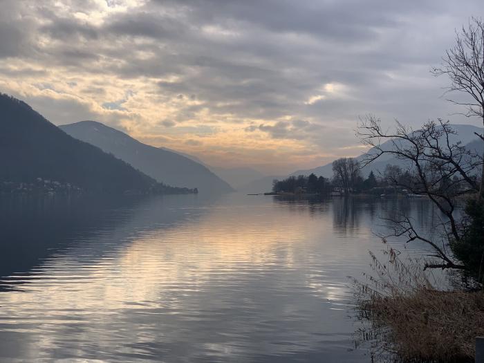 Lago al tramonto con le montagne e le nuvole riflesse