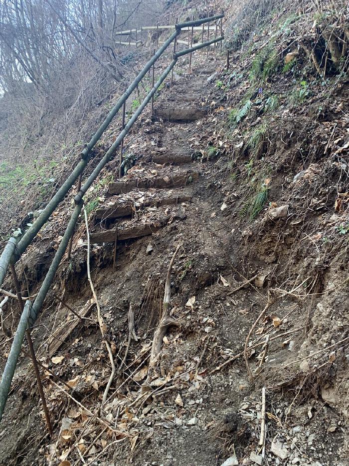 Scalinata di legno e terra in un sentiero ripido con corrimano