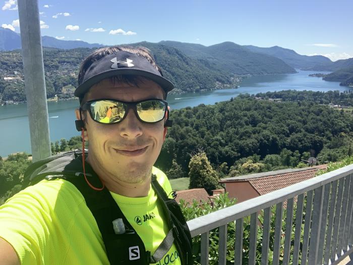 Selfie con cappellino, occhiali da sole e maglia gialla fluo sopra il lago